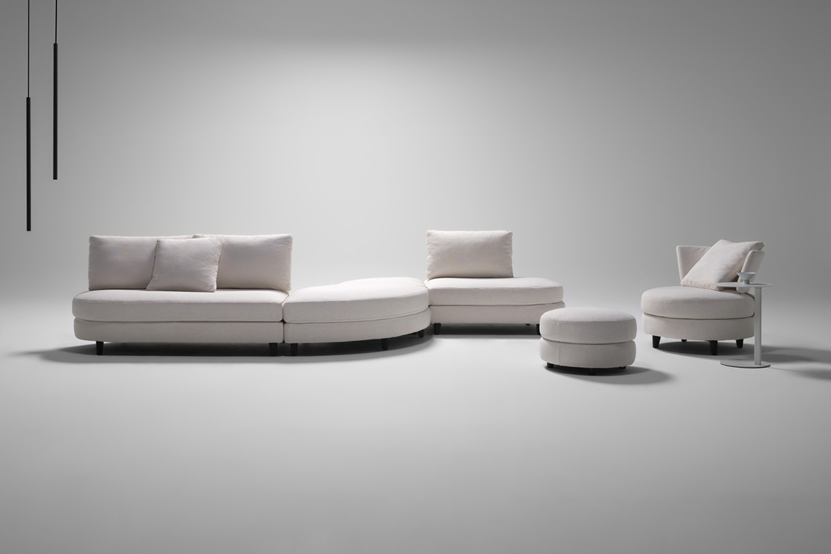Curved s-shape modular sofa in a minimalist futuristic setting. Contemporary sofa is styled in a white fabric.