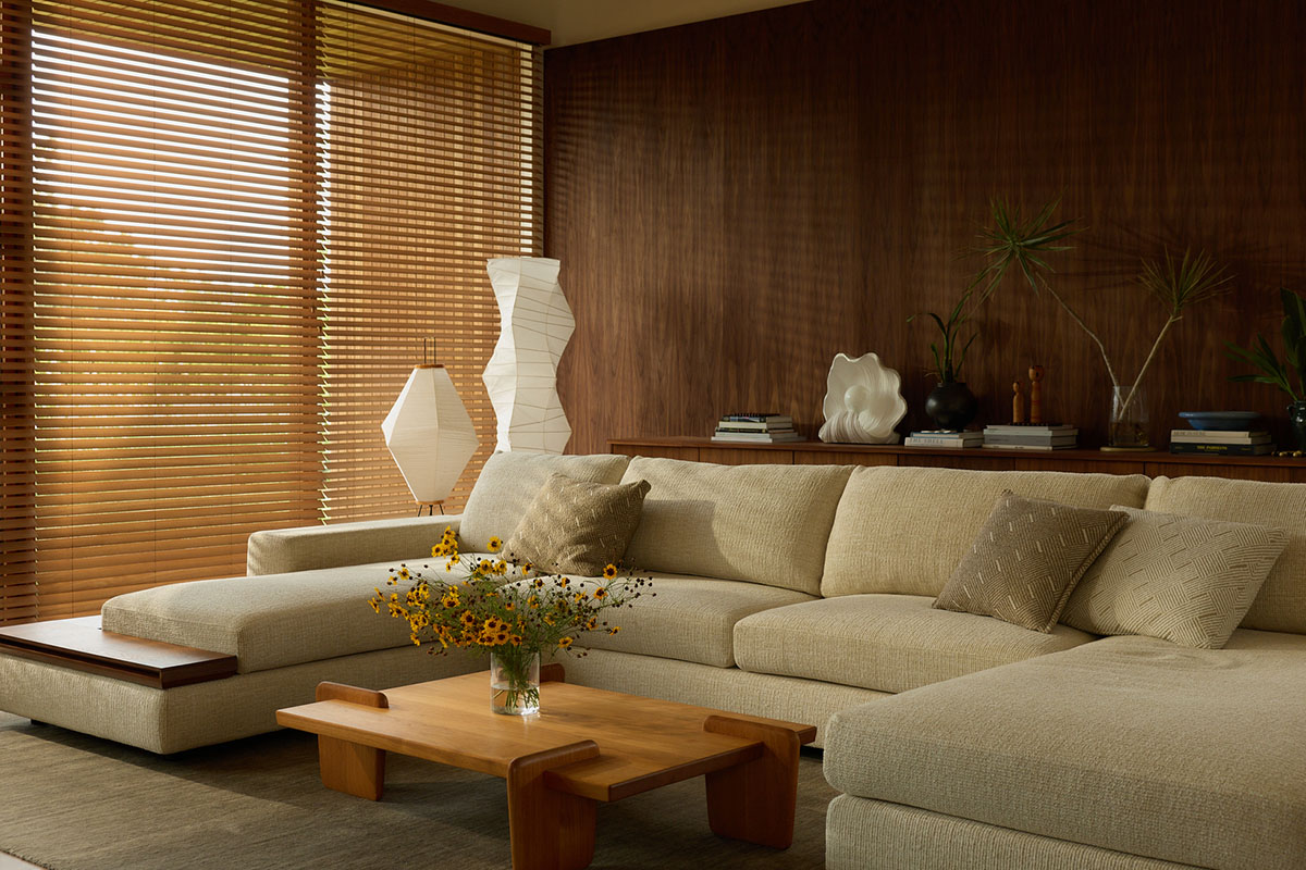 Modular sofa with integrated timber shelving styled in a beige fabric in an organic-inspired living space with mixed timber walls and coffee table.