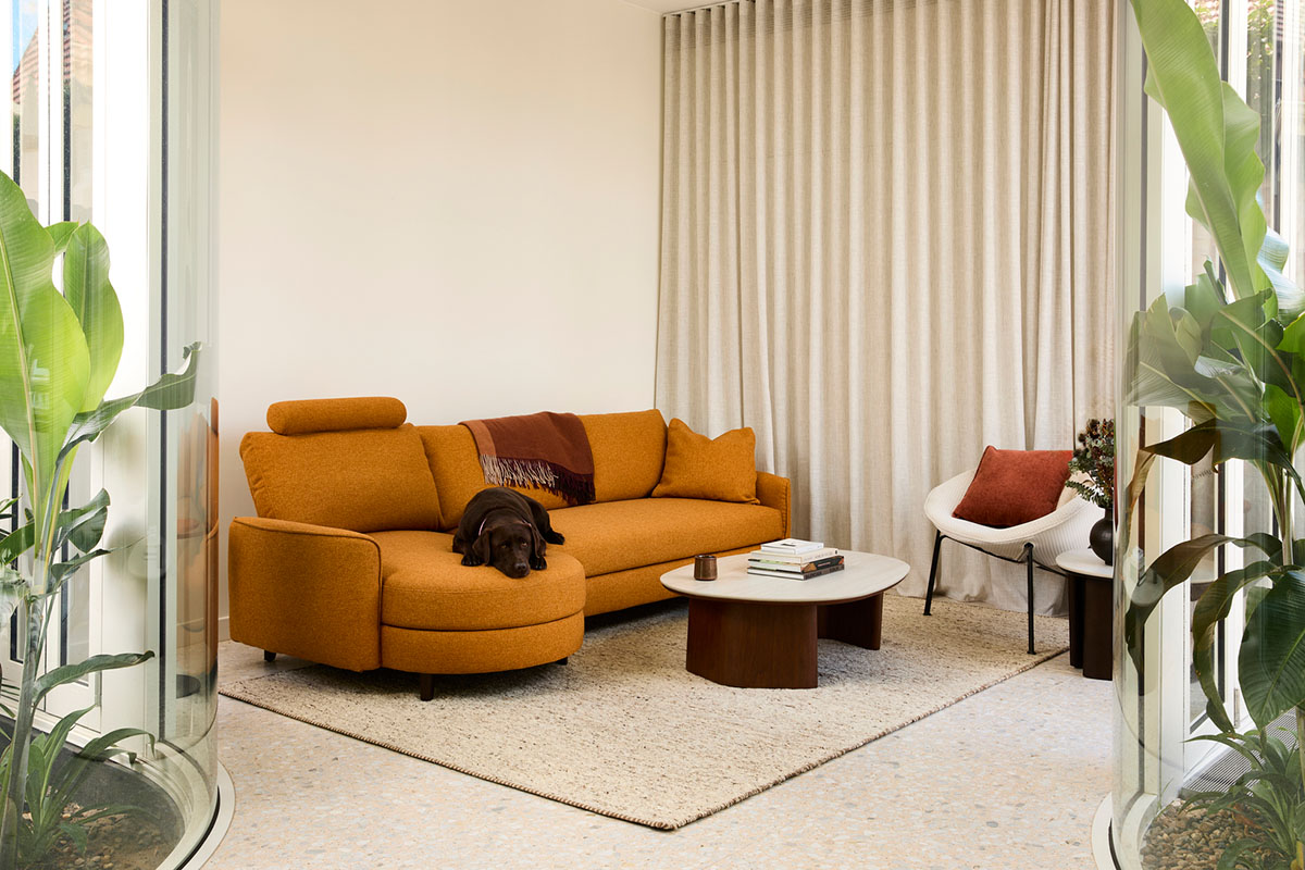 Modular curved sofa with storage and headrest in a warm orange fabric styled in a compact apartment.