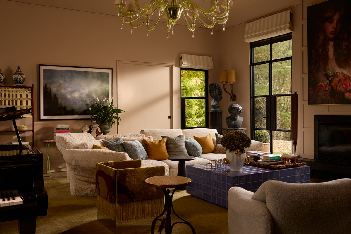 Maximalist interior styled with one sofa in two fabrics and eclectic décor, a vintage chandelier and mixed materials.