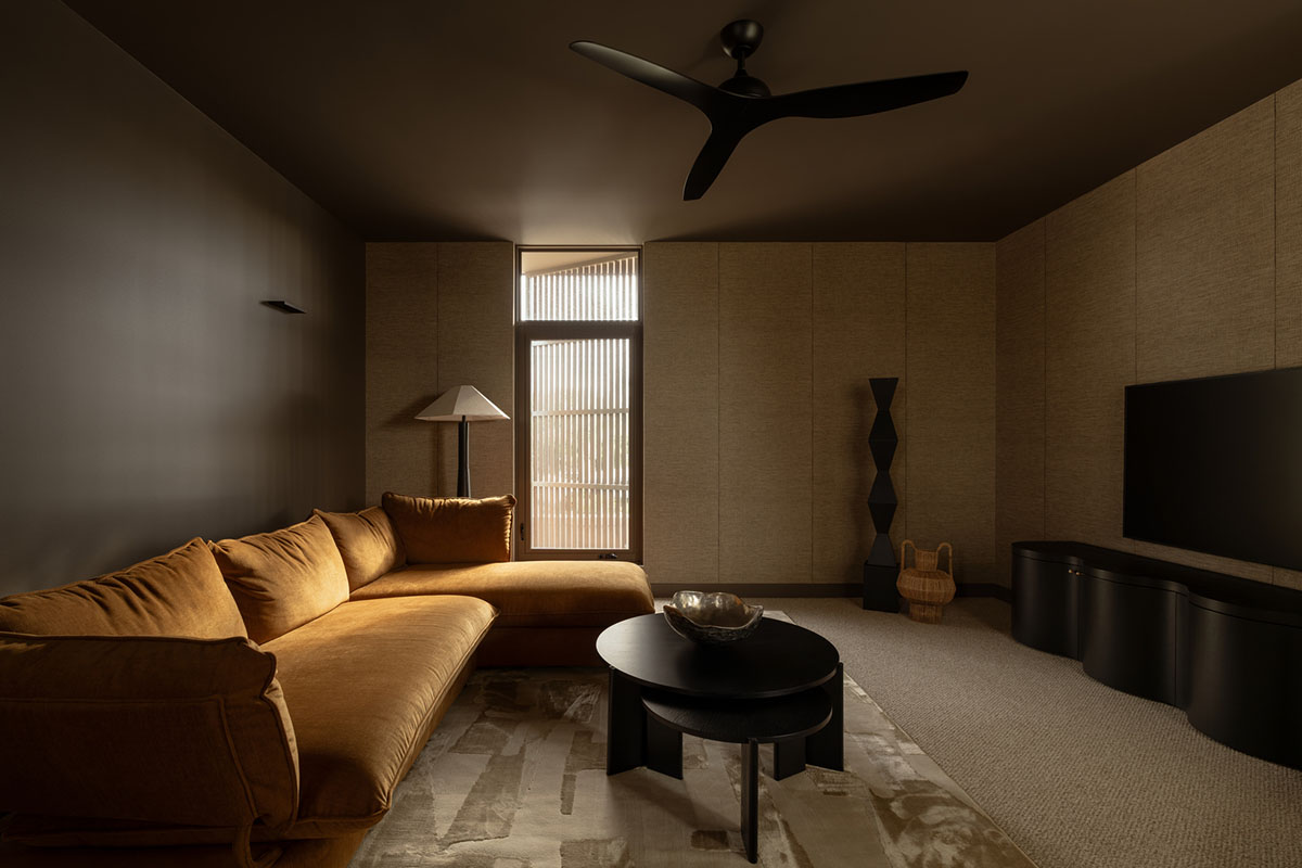 Dark and moody interior with brown colour drenched wall, dark timber coffee table and a comfortable sofa in tobacco toned velvet fabric.