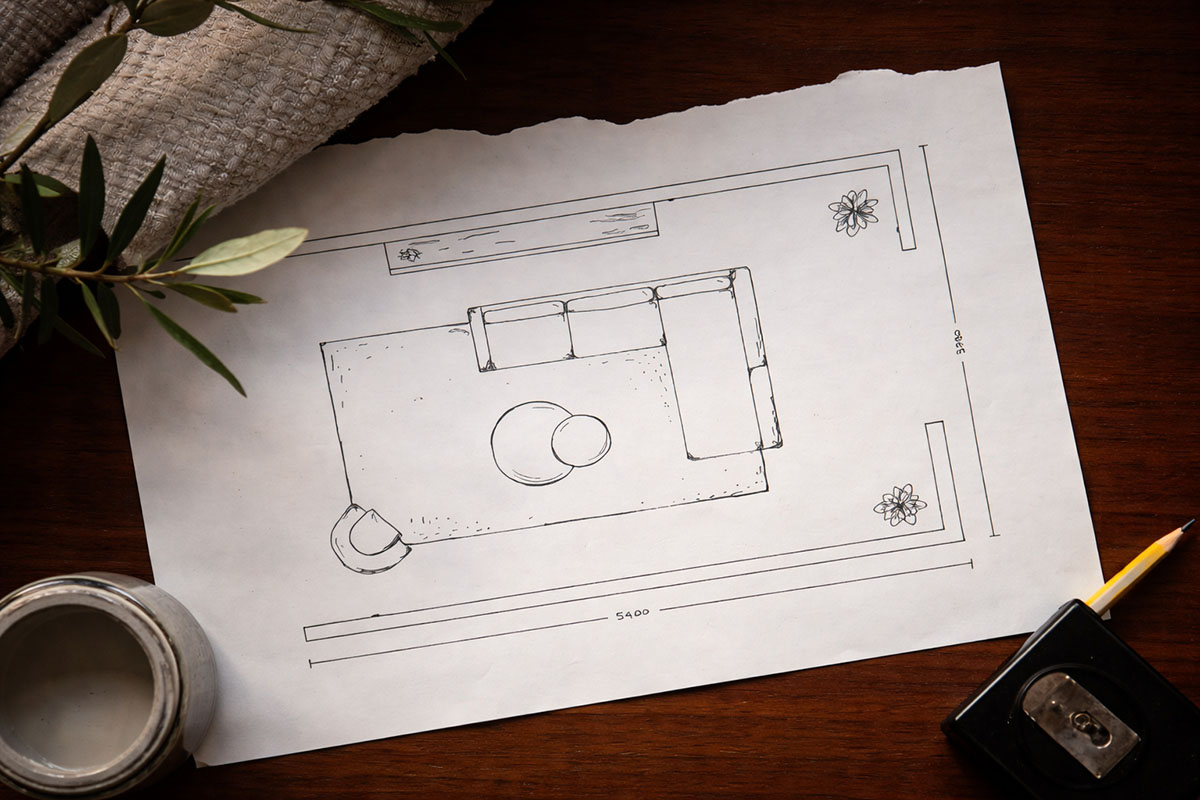 : Overhead shot of a sketched floorplan, showcasing modular sofa styled in rectangular living room with rug, ottomans and chair.