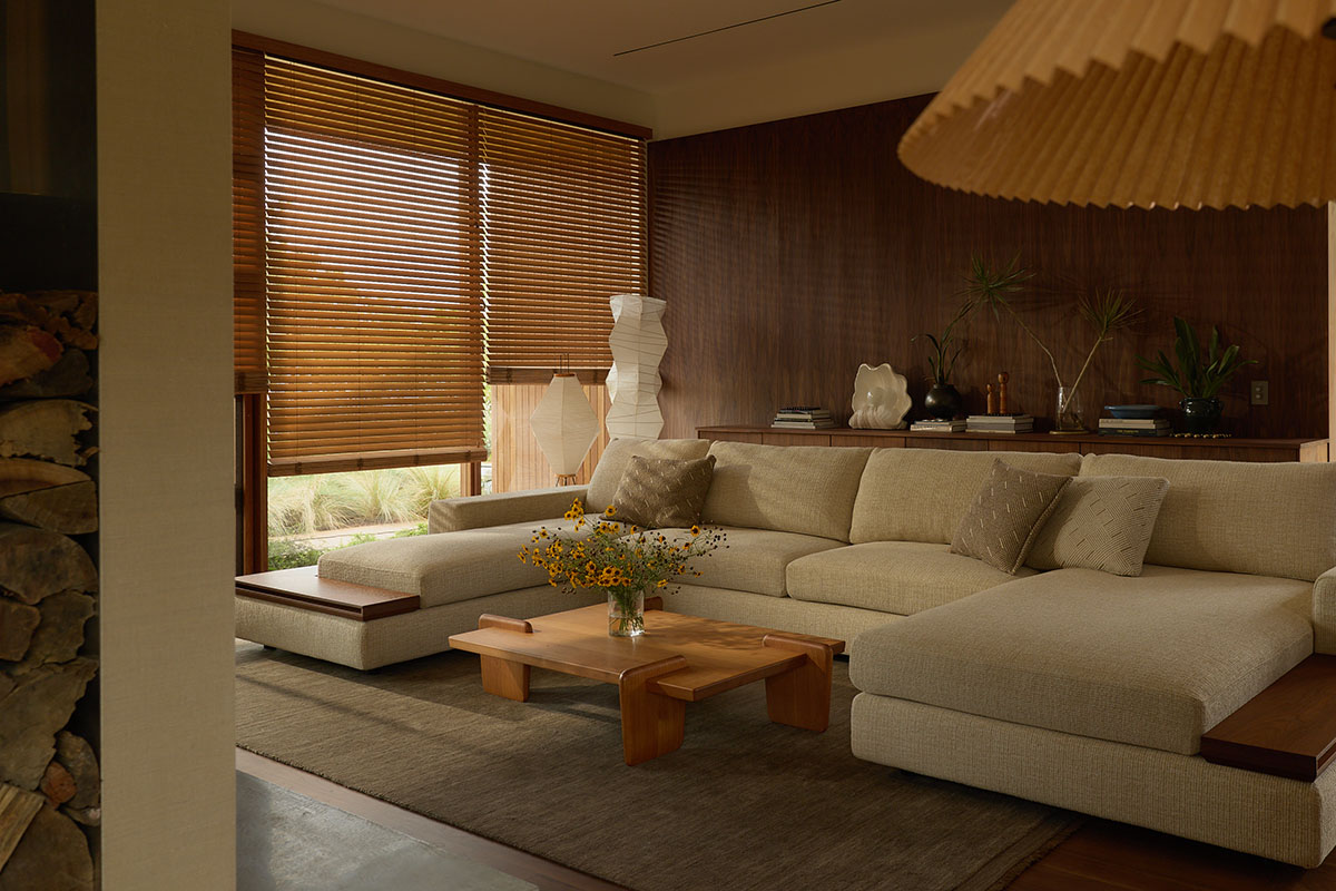 Comfortable U-shaped modular sofa with deep seats styled in a warm neutral fabric. Living room is low-lit and warm.