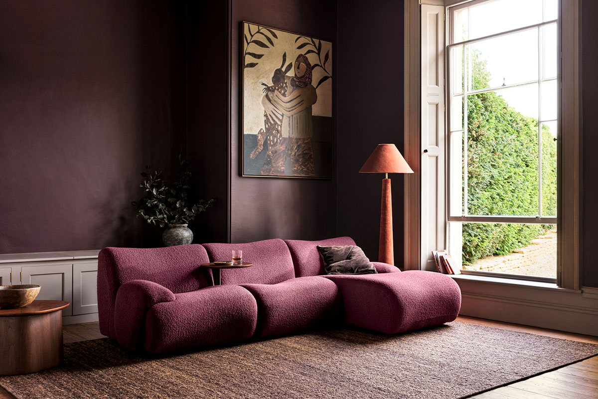 A deep maroon, dark burgundy colour drenched room styled with a modular sofa. A perfect setup for a cosy movie night.