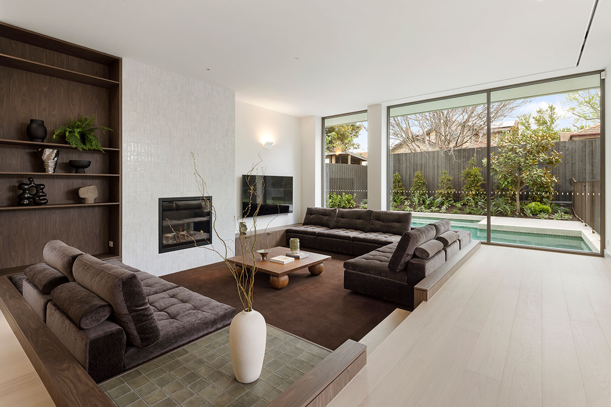 A modern sunken lounge styled in deep chocolate tones. Sofa features deep, tufted seats ideal for family movie nights.