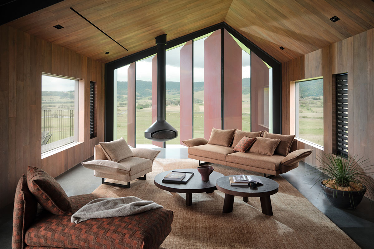 Rustic earthy living space styled with hanging fireplace, 3 seater sofa and armchair in warm spice fabrics.