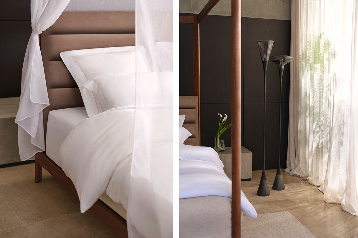 Four poster bed framed by canopy and flowing sheer drapery, with sculptural glass floor lamps.