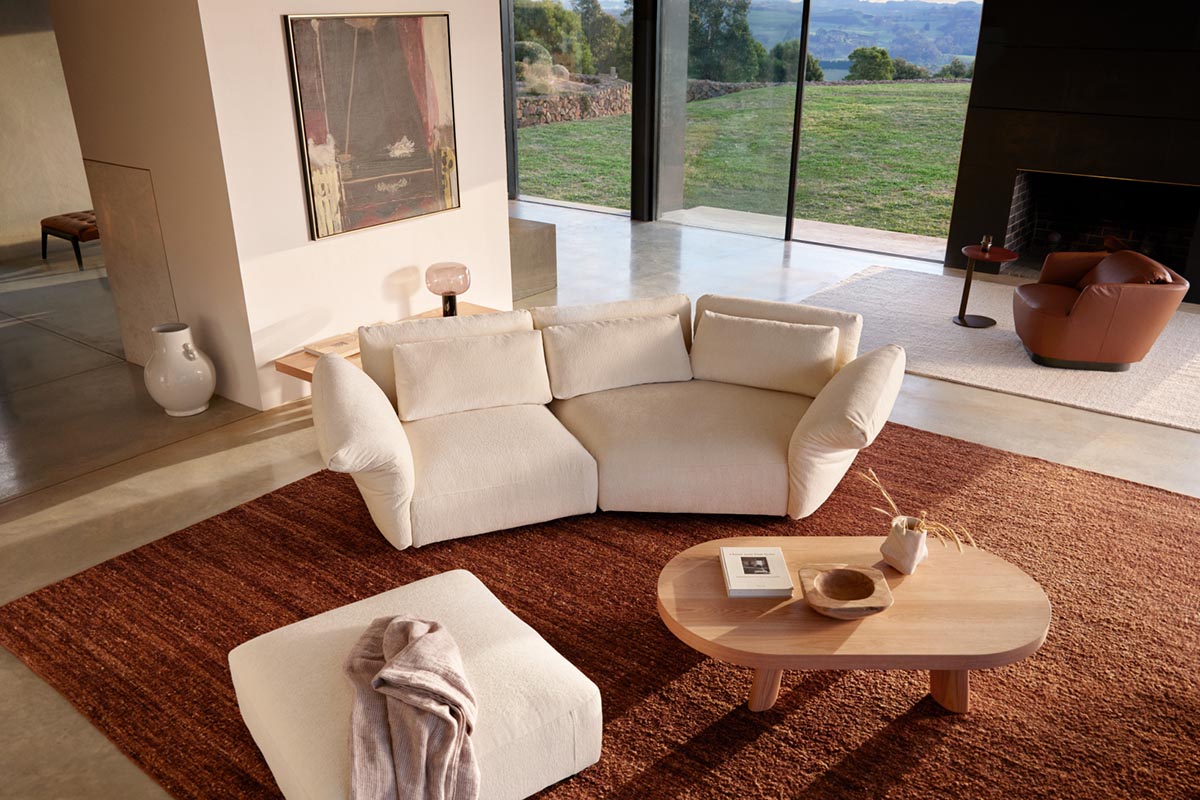 Light-filled living room styled with Scandinavian principles, a beige sofa with chaise and rust-toned rug create natural warmth.