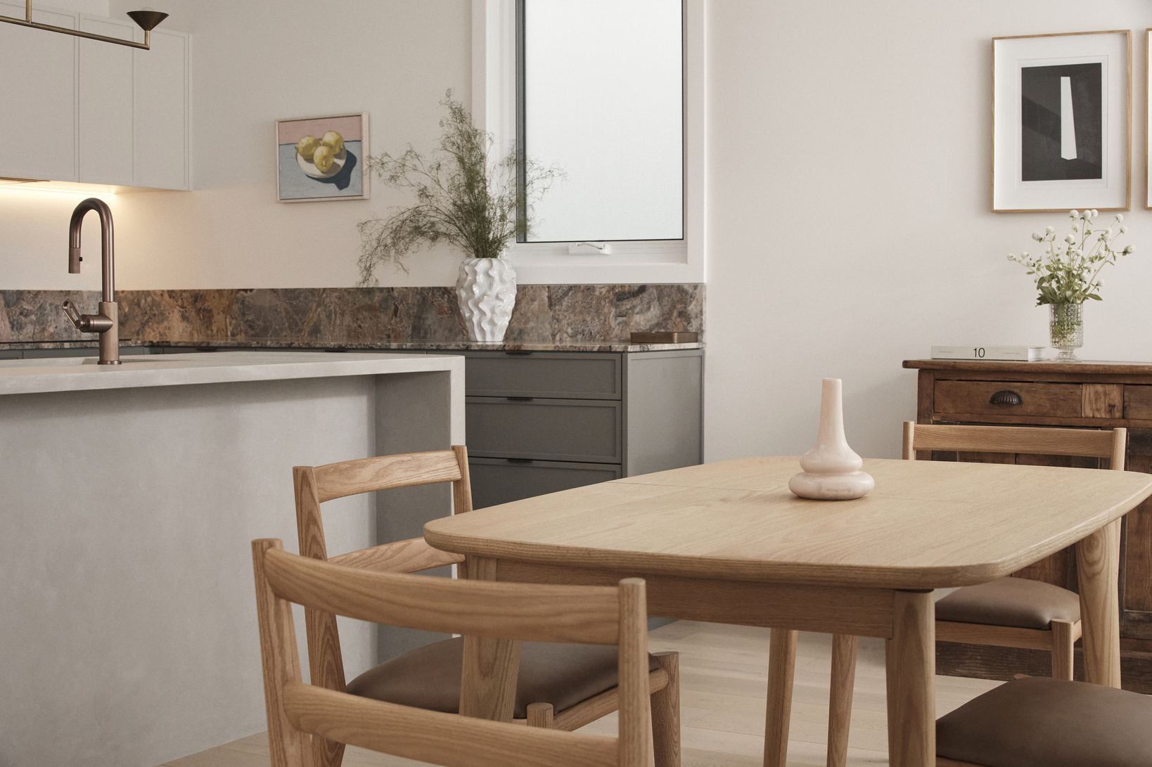 Light timber dining setting in an open plan kitchen, contemporary and minimalistic, styled with ceramic vases and tall plants.
