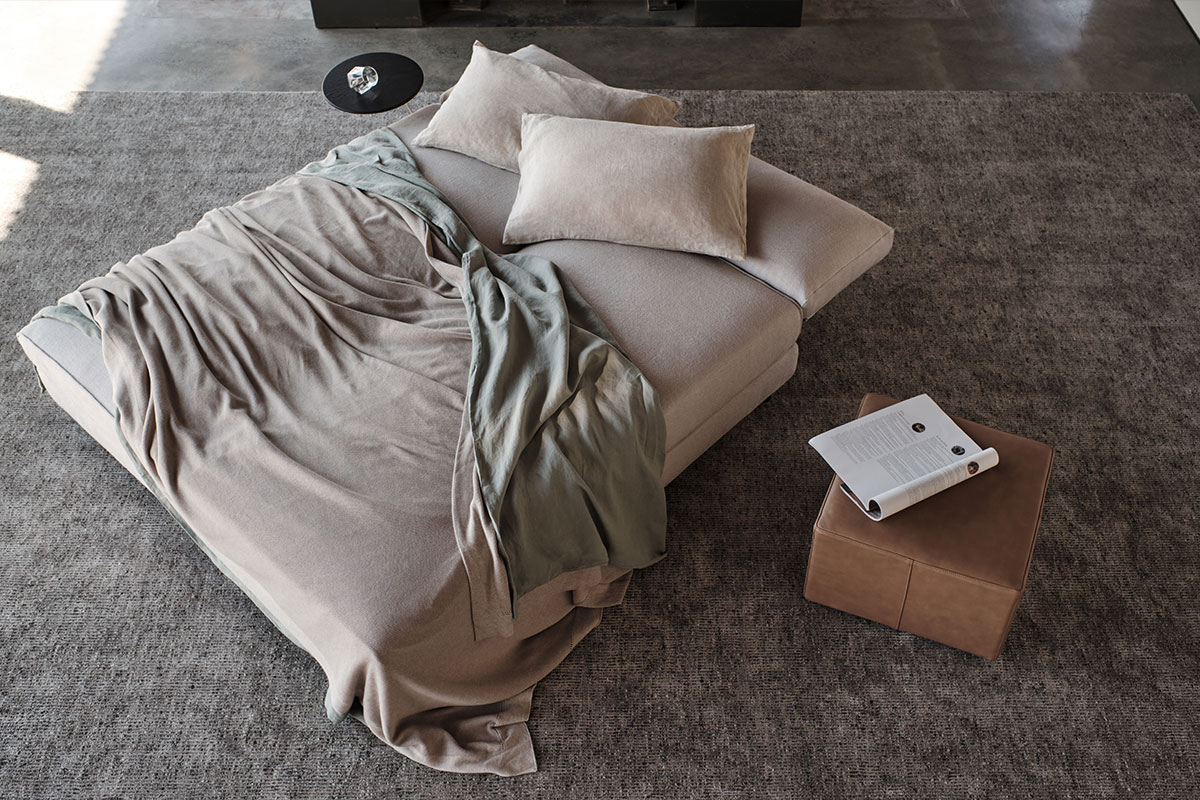 A modular sofa that has been rearrange into a bed in the centre of a living room.