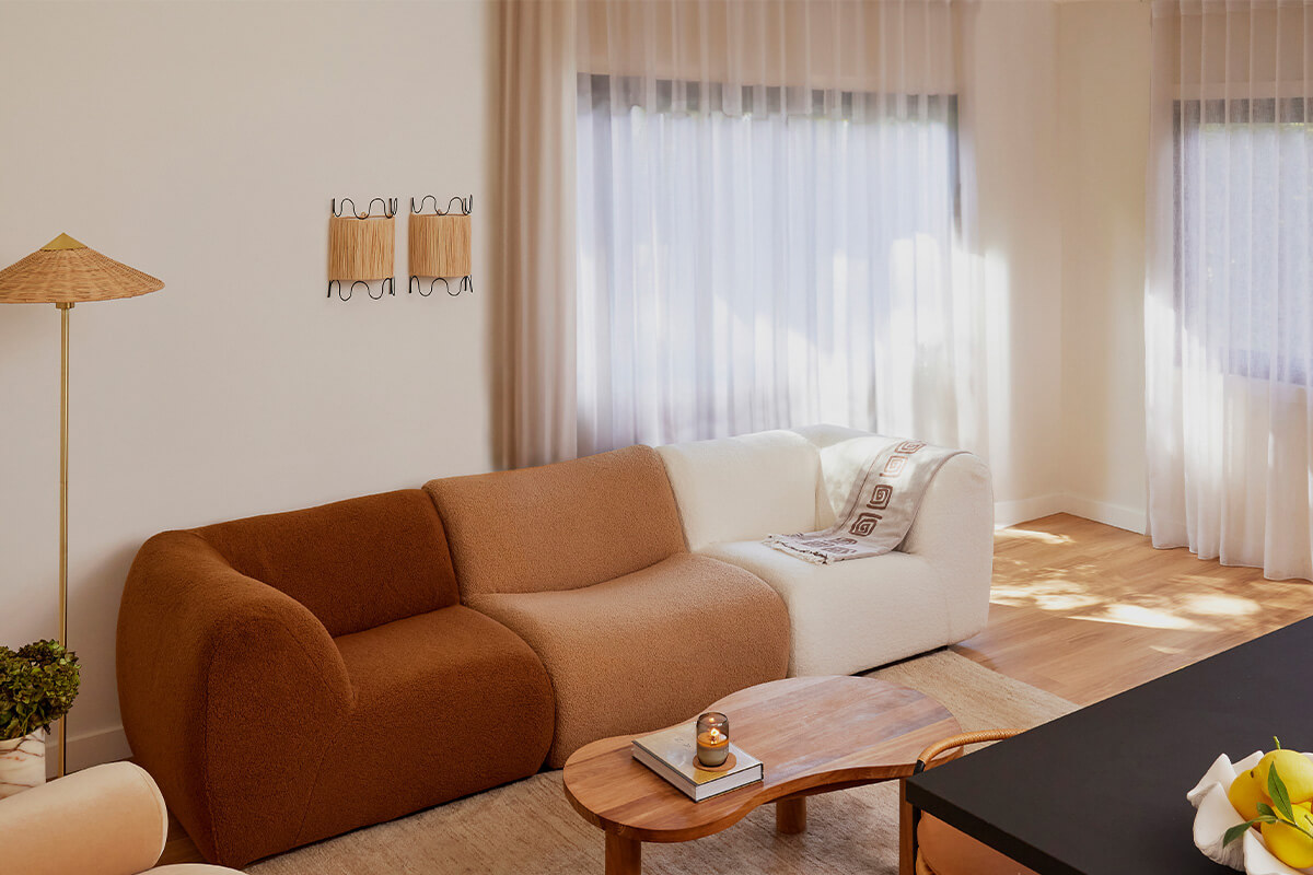 A modular sofa with low-profile curves styled in three bouclé fabrics in a palette of warm tonal neutrals.