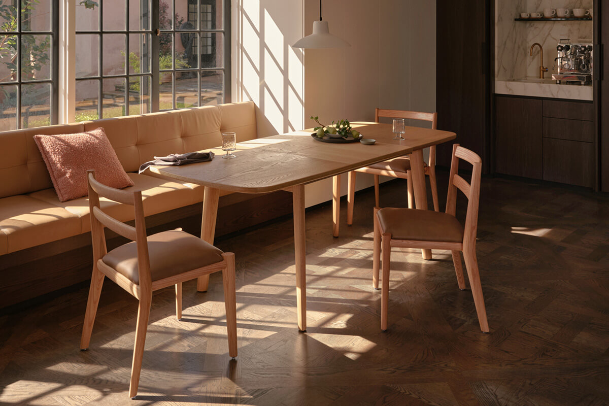 Soft neutral living space with natural oak coffee tables. Sunlit dining area with a light timber extendable table, paired with warm tan seating.