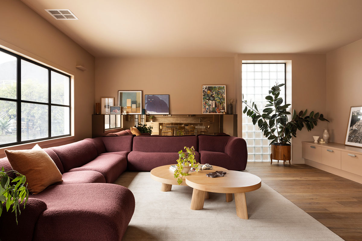 Eclectic living room with a plum coloured modular sofa and various artwork and plants.