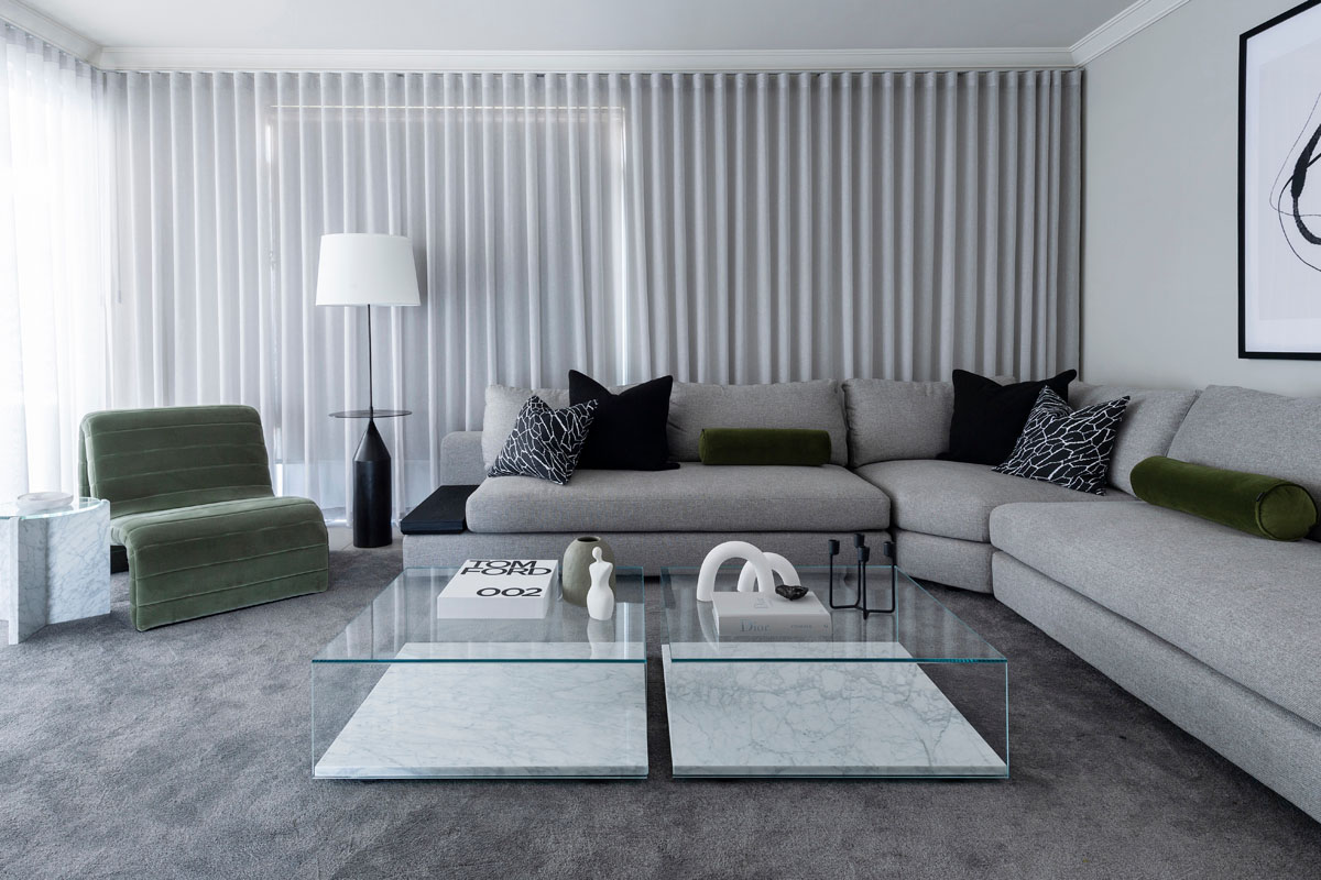Contemporary living room featuring a grey modular sofa, marble coffee tables, and minimalist decor.